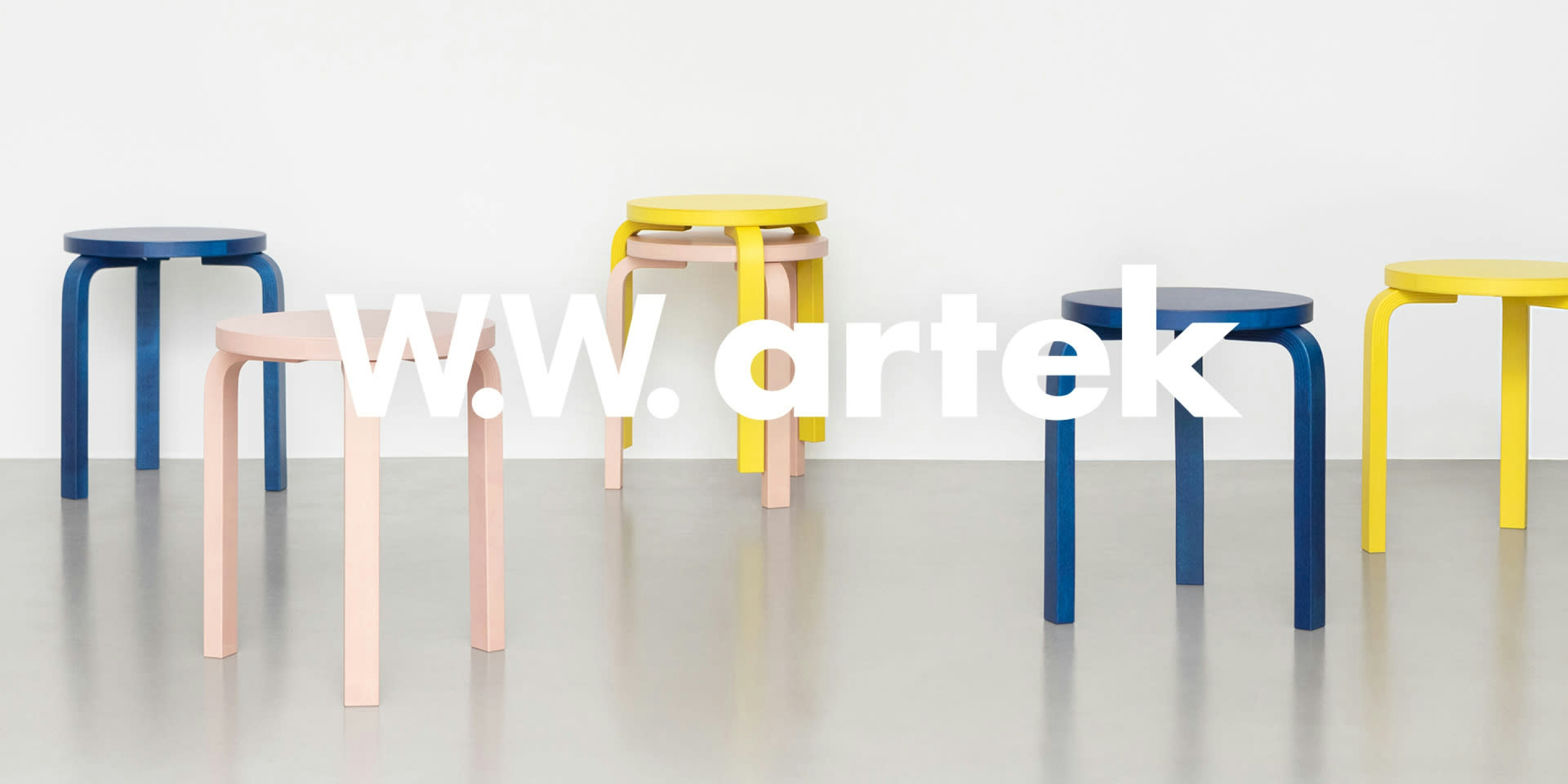 The image features a clean, minimalist setting showcasing colorful Artek stools in blue, pink, and yellow against a white background. The text "W.W. Artek" is placed prominently across the image. The arrangement emphasizes the iconic design of the stools with a focus on simplicity and color contrast.